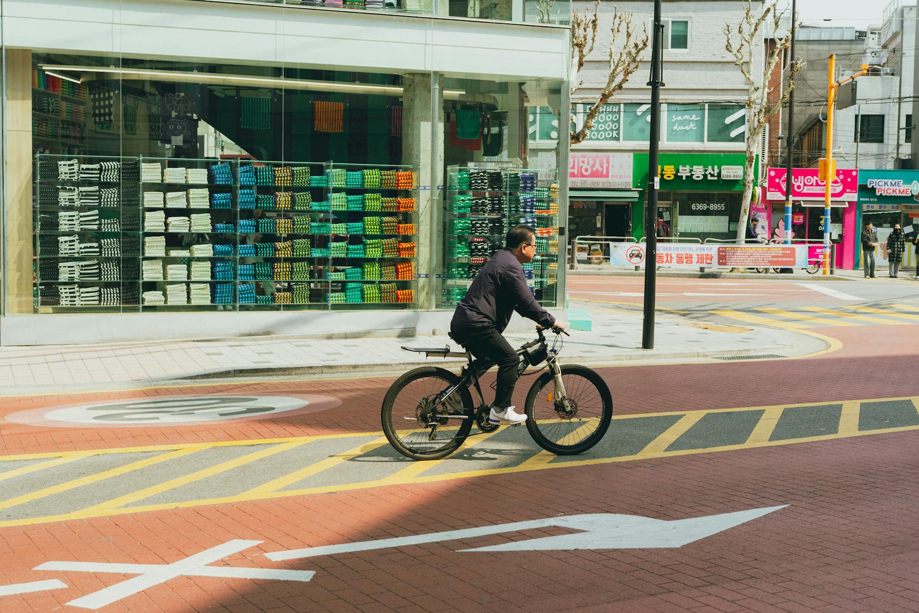 Person cycling past colorful shops in downtown Seoul