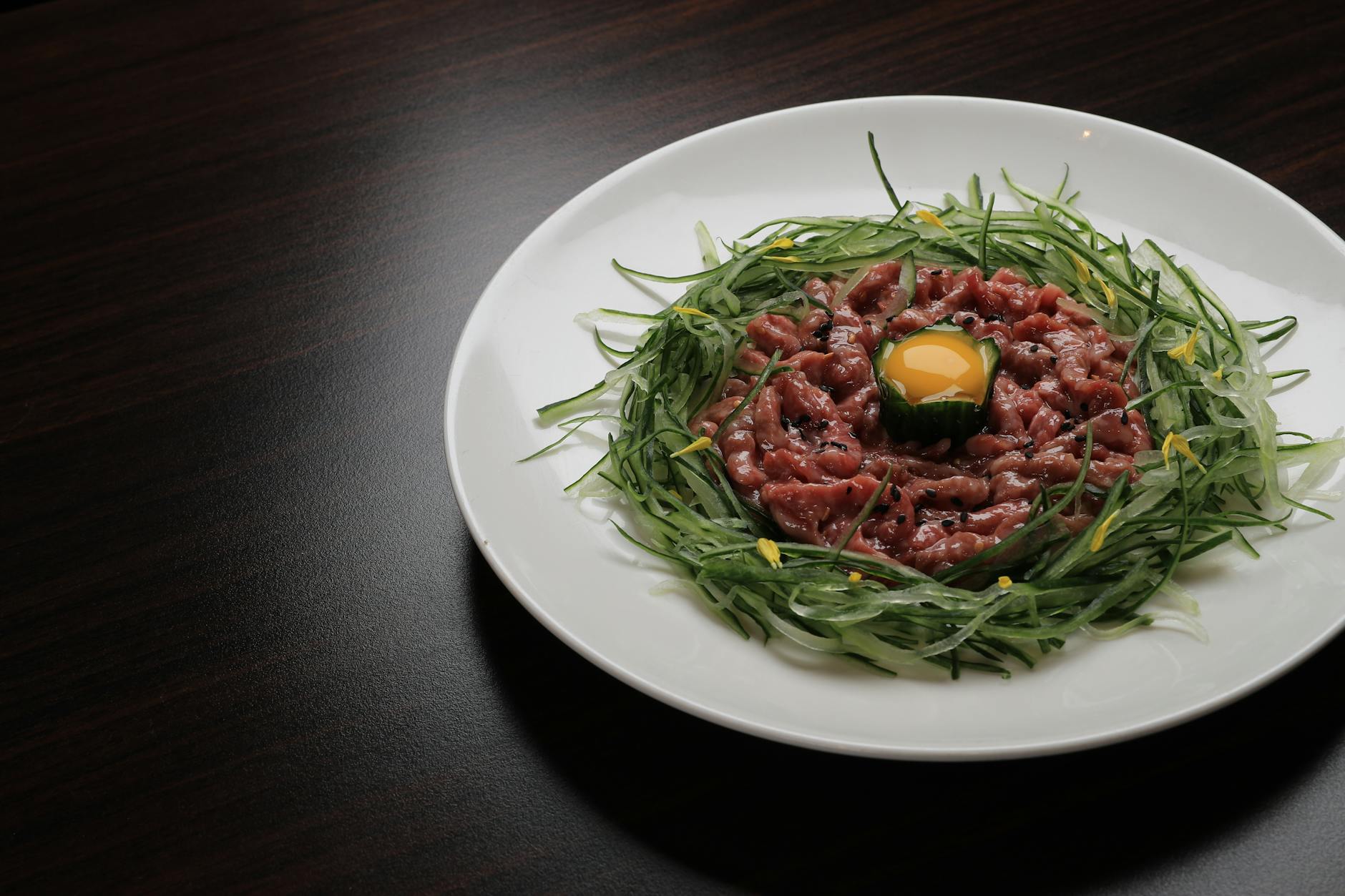 Plate of Korean yukhoe beef tartare with raw egg yolk and sesame