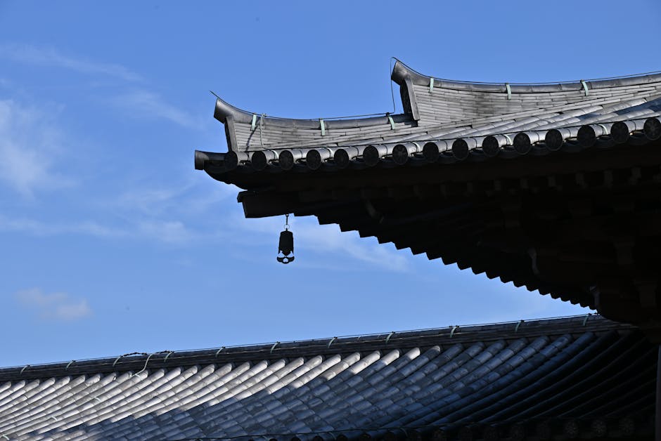 Korean temple rooftop with classic hanging bell against a clear blue sky