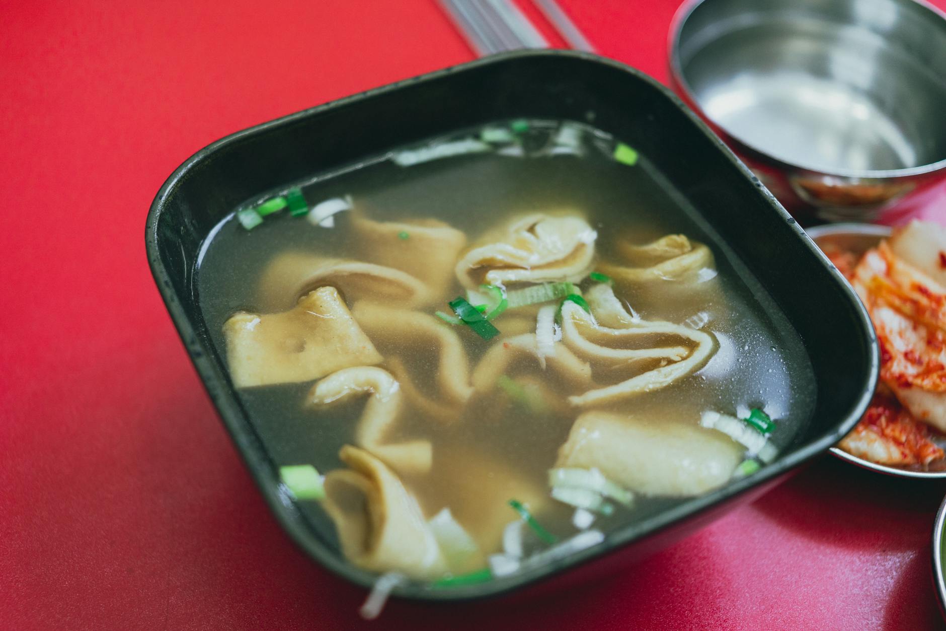 Skewers of Korean odeng fish cake simmering in broth at a street stall