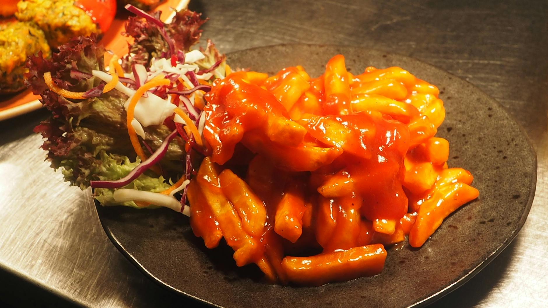 Plate of bright red tteokbokki Korean spicy rice cakes with fish cake