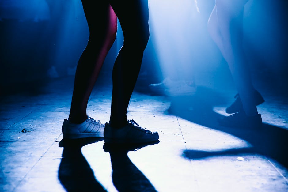 Silhouettes of people dancing on a Seoul nightclub floor bathed in blue lighting