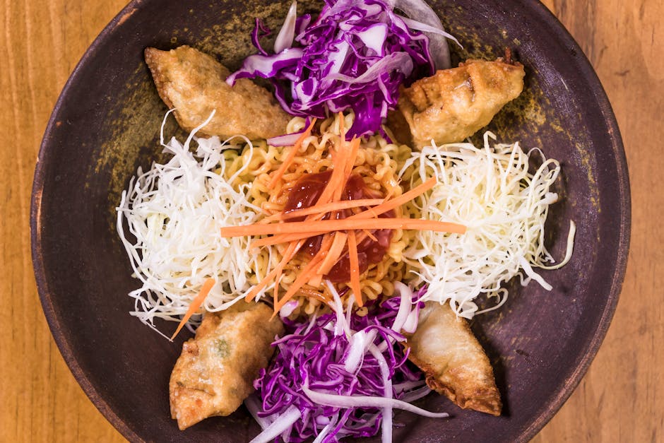 Top view of colorful Korean noodle bowl with dumplings cabbage carrot