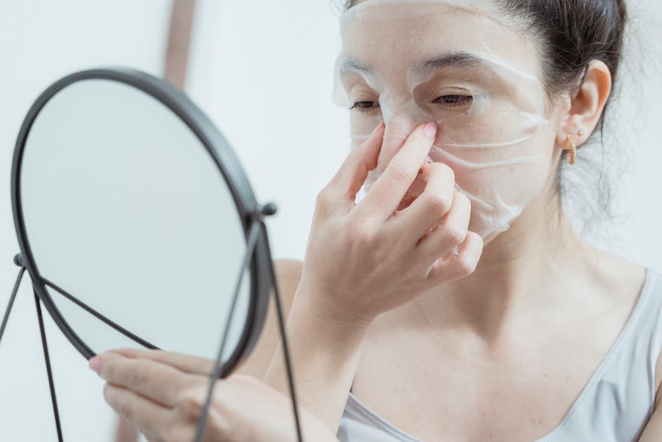 Woman applying a K-beauty facial sheet mask in front of a bathroom mirror