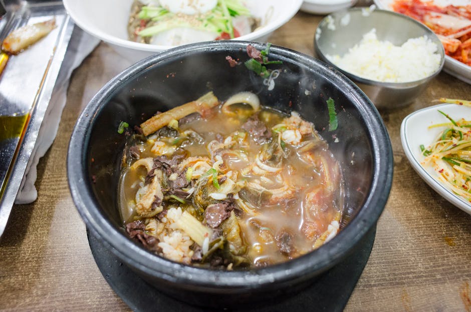 Steaming hot bowl of traditional Korean spicy soup with side dishes