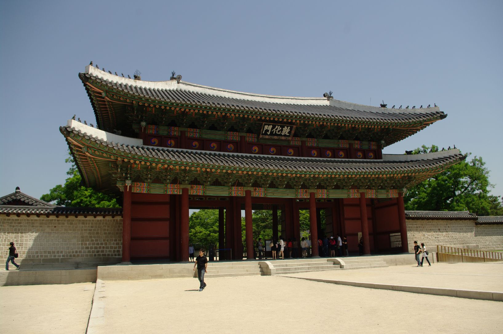 Donhwamun, the two-storey main gate of Changdeokgung Palace, with red wooden doors and a sandy forecourt