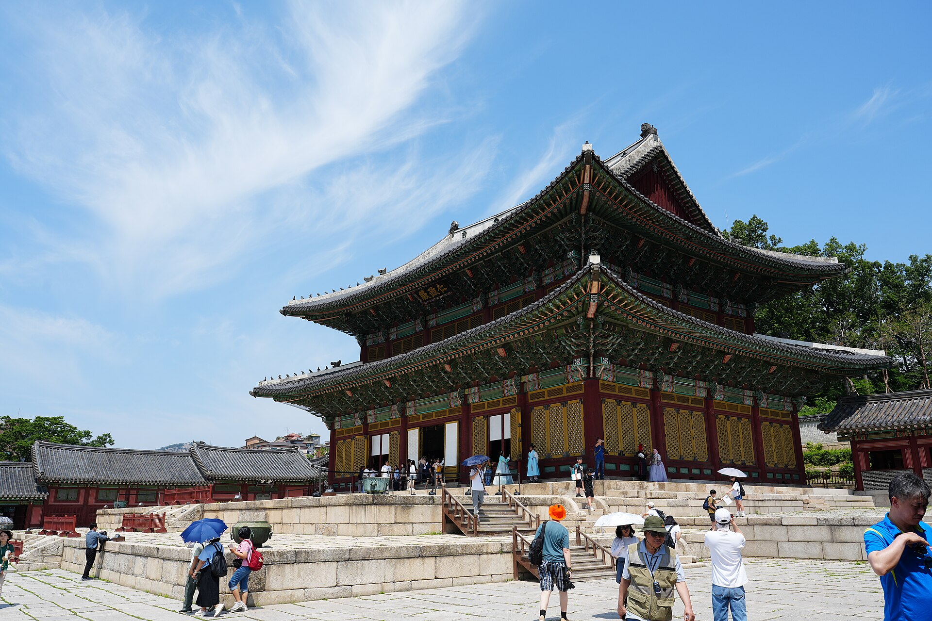 Injeongjeon throne hall at Changdeokgung Palace with visitors in hanbok on its stone terrace