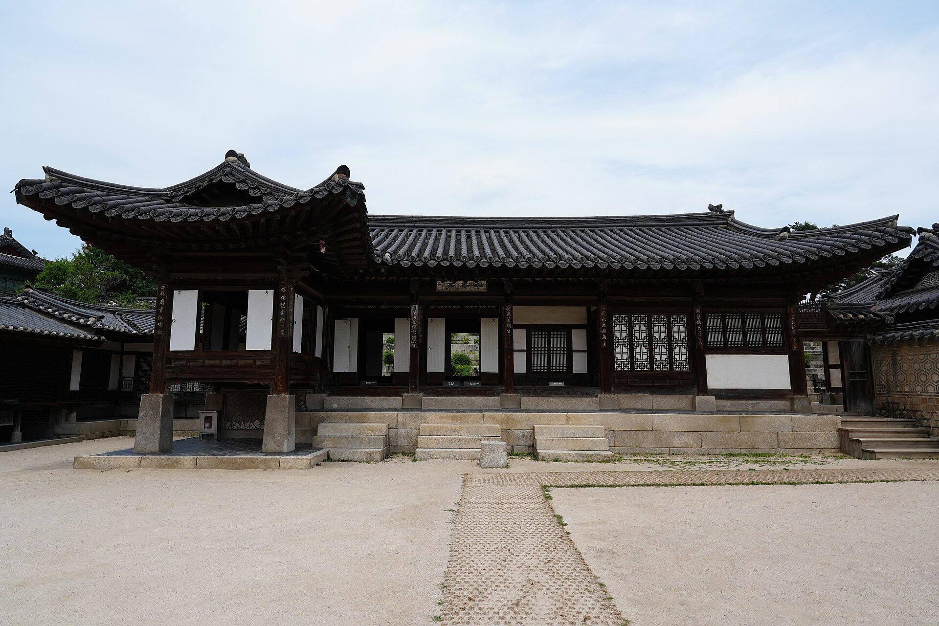 The unpainted timber buildings of Nakseonjae at Changdeokgung, with latticed windows, stone steps and a raked earth courtyard