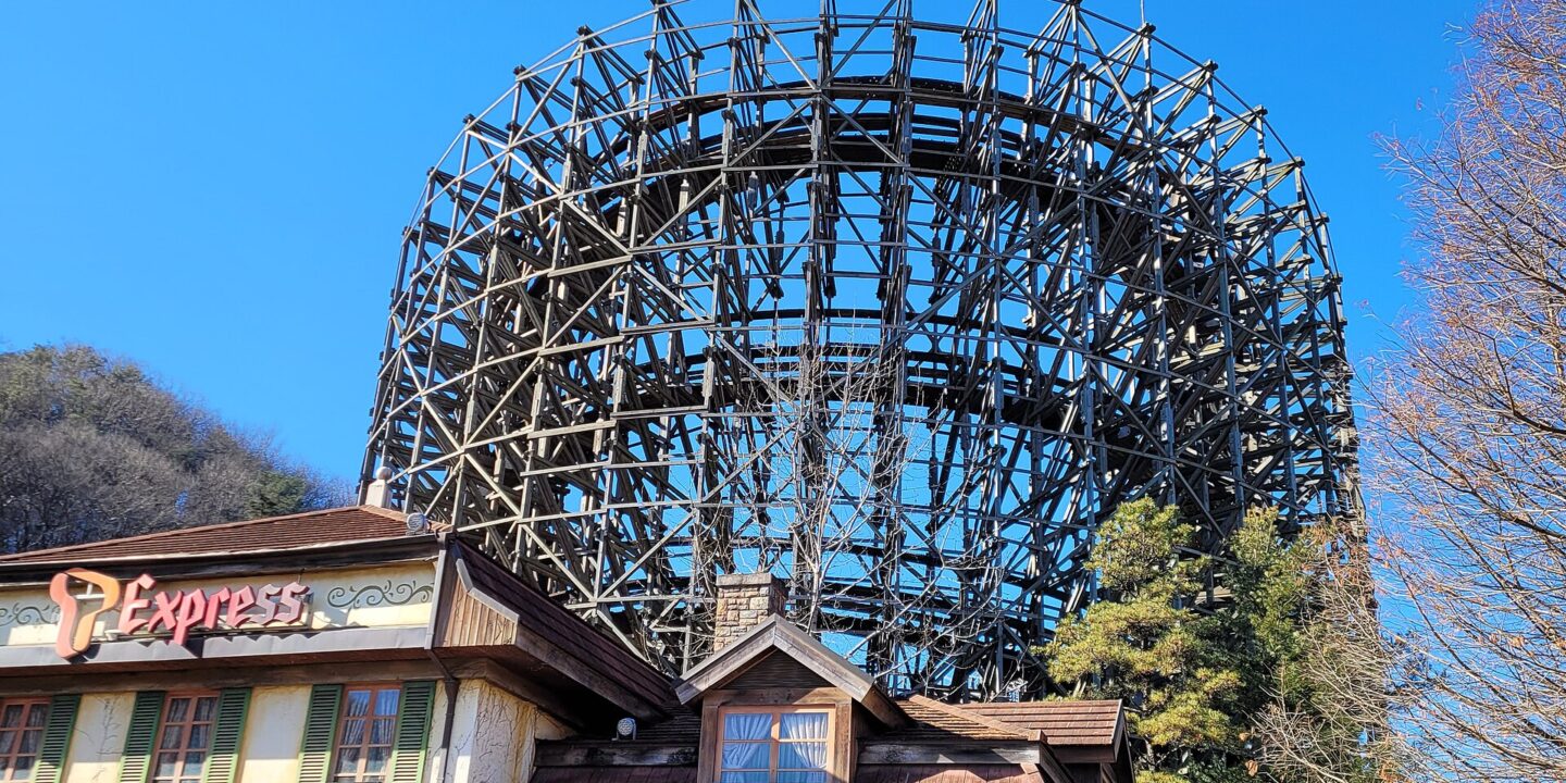 The timber lattice of the T Express wooden roller coaster rising behind its station building at Everland under a clear blue sky