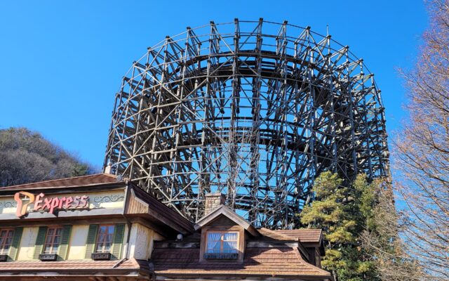 The timber lattice of the T Express wooden roller coaster rising behind its station building at Everland under a clear blue sky