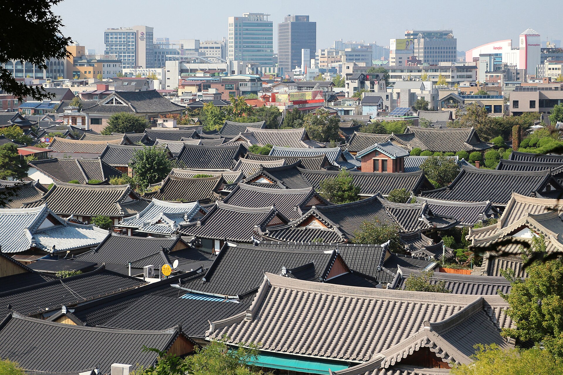 Sea of dark tiled hanok roofs in Jeonju Hanok Village with modern city buildings behind