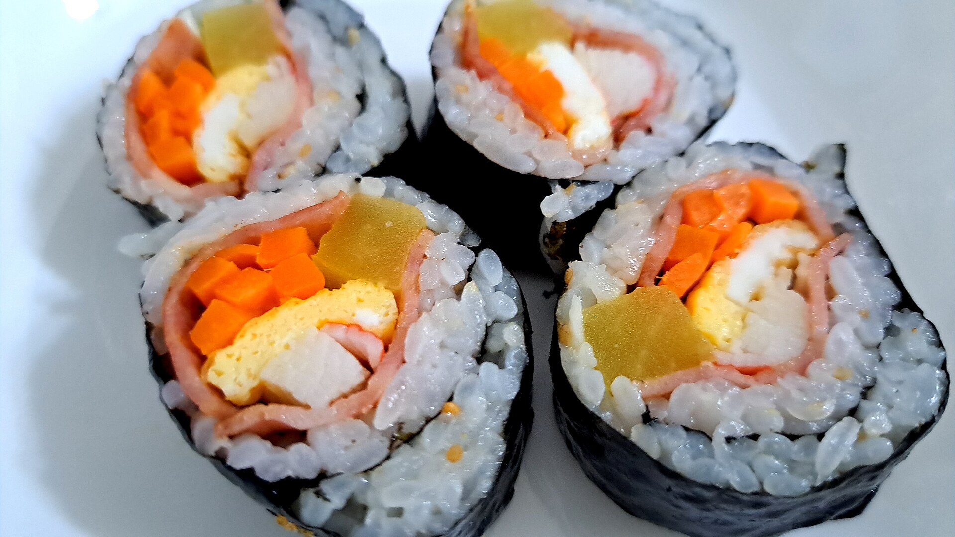 Close-up of sliced Korean gimbap rolls with egg, carrot, pickled radish and ham