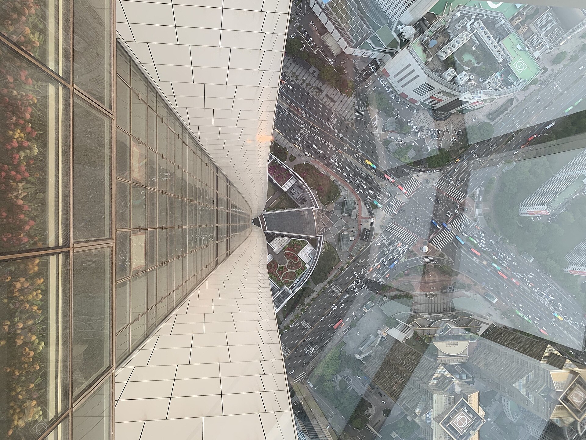 Looking straight down the glass-and-steel facade of Lotte World Tower to the streets and buildings far below