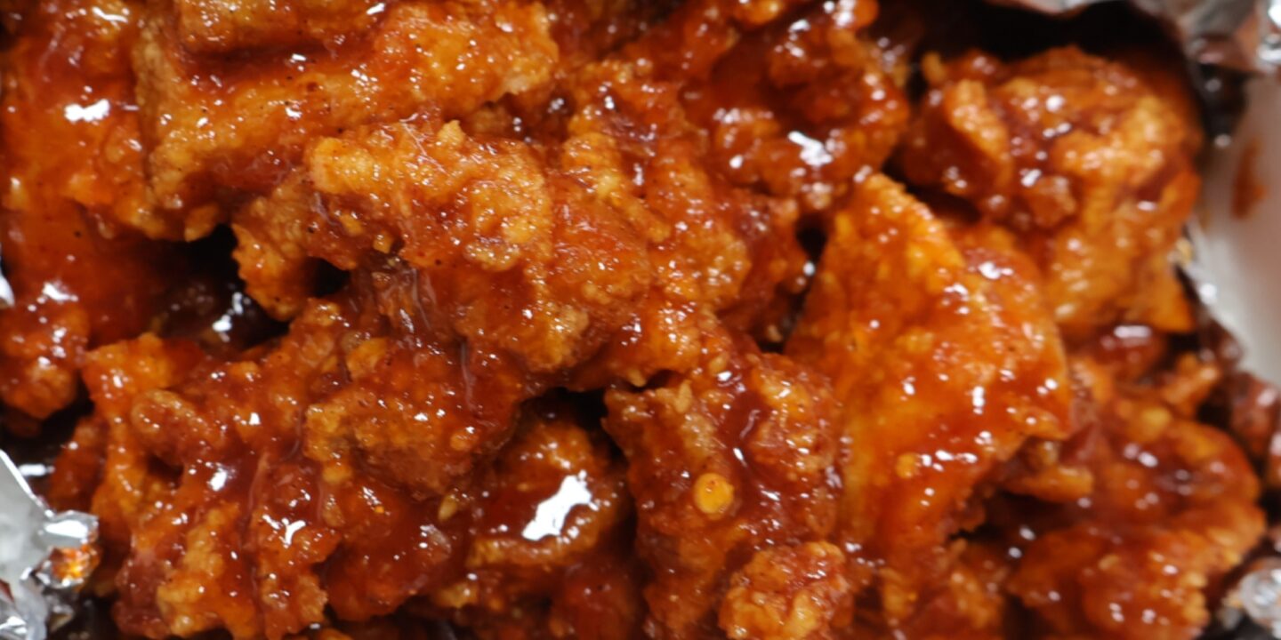 Close-up of Korean fried chicken pieces coated in glossy red yangnyeom sauce